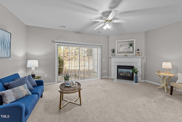 carpeted living room featuring ceiling fan and a tiled fireplace