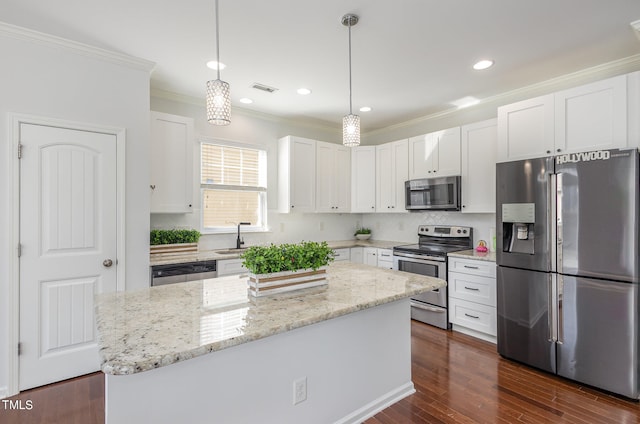 kitchen featuring white cabinetry, appliances with stainless steel finishes, decorative light fixtures, and a kitchen island