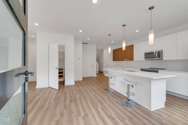 kitchen featuring stainless steel appliances, an island with sink, and white cabinetry