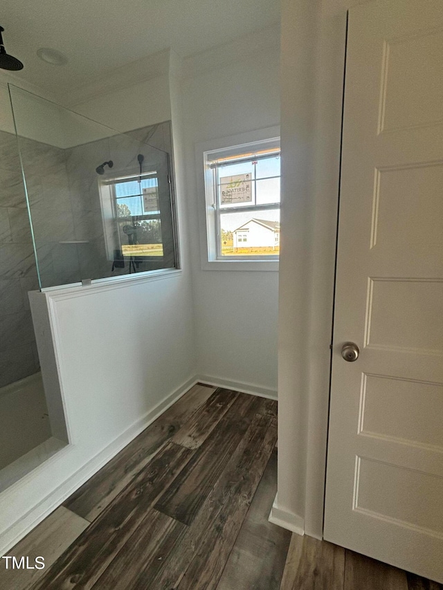 bathroom with tiled shower, crown molding, and hardwood / wood-style flooring