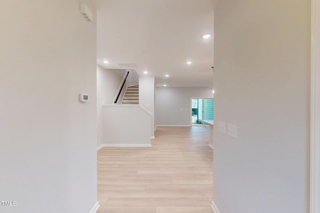 corridor featuring light wood-style floors, recessed lighting, baseboards, and stairs