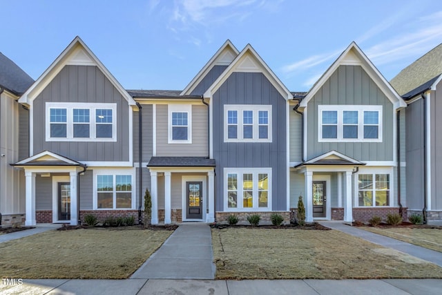 view of front of home featuring brick siding, board and batten siding, and a front yard