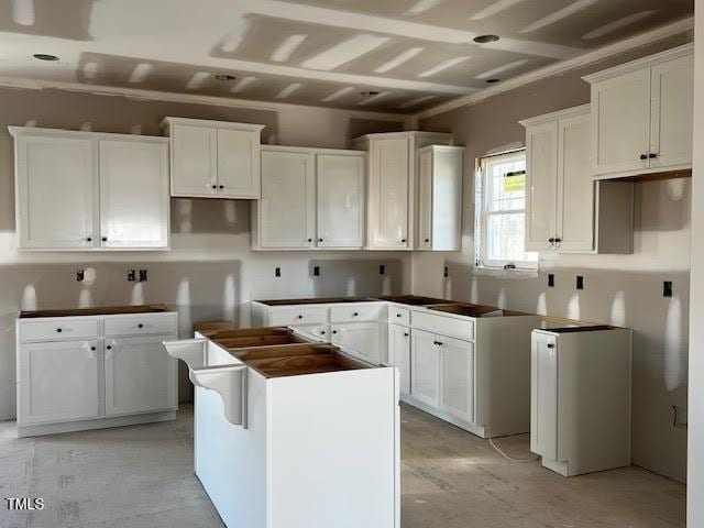 kitchen featuring refrigerator, a kitchen island, and white cabinets