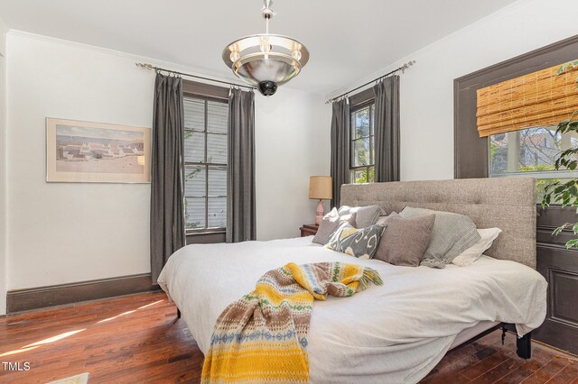 bedroom featuring an inviting chandelier, crown molding, and dark hardwood / wood-style flooring