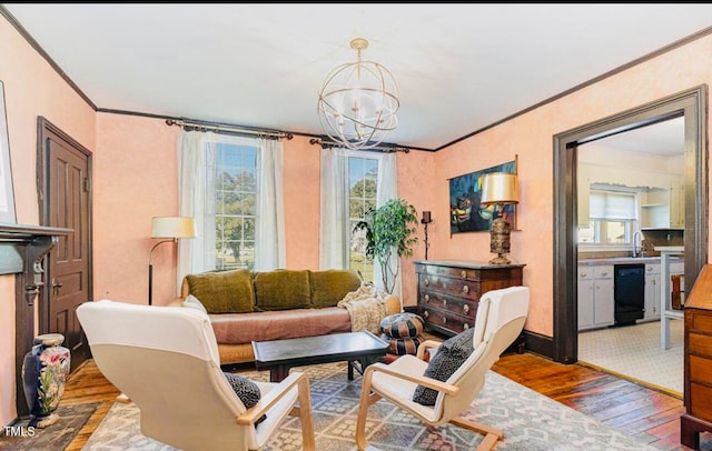 living room with ornamental molding, a notable chandelier, hardwood / wood-style floors, and sink