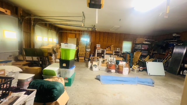 garage with a garage door opener and wood walls