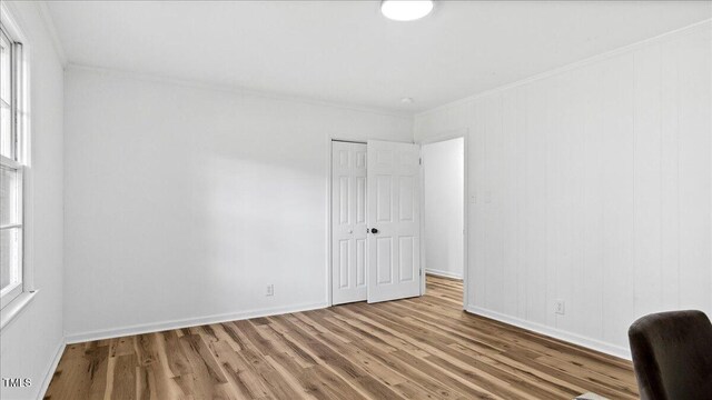 empty room featuring light wood-type flooring, plenty of natural light, and crown molding