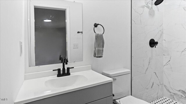 bathroom featuring vanity, toilet, and tiled shower