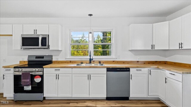 kitchen featuring white cabinetry, sink, stainless steel appliances, and decorative light fixtures