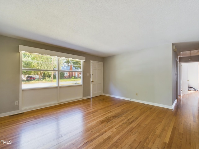 spare room featuring light hardwood / wood-style floors and a textured ceiling