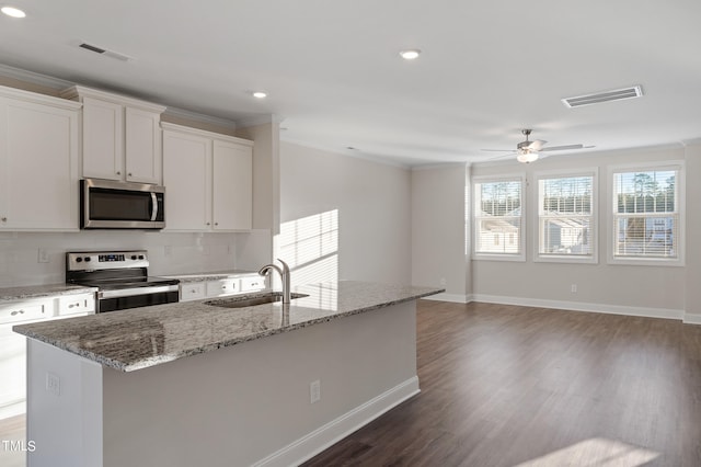 kitchen with appliances with stainless steel finishes, backsplash, a kitchen island with sink, sink, and white cabinets