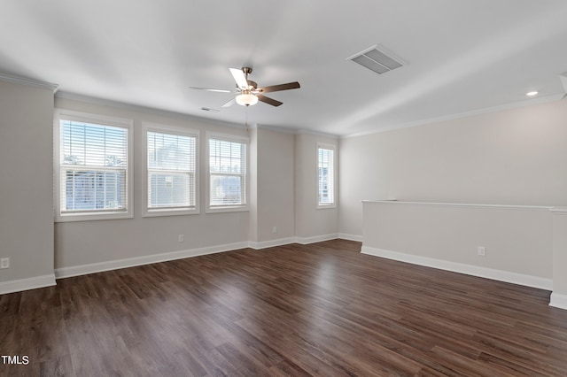 empty room with a wealth of natural light, dark wood-type flooring, and ornamental molding