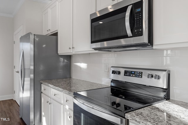 kitchen featuring white cabinets, crown molding, appliances with stainless steel finishes, dark hardwood / wood-style flooring, and light stone counters