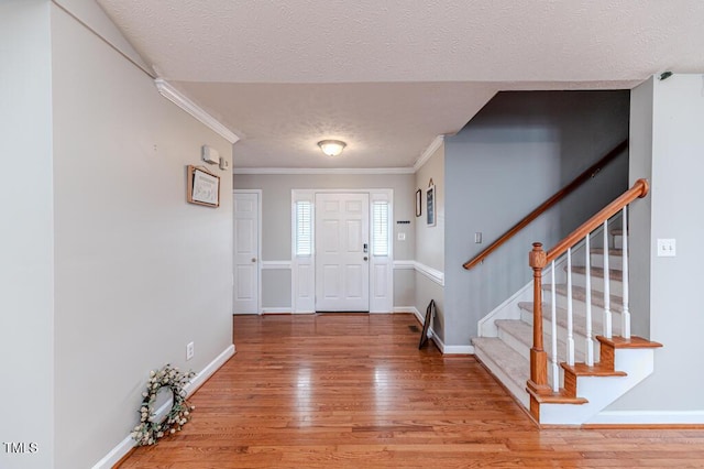 foyer entrance with hardwood / wood-style flooring, crown molding, and a textured ceiling