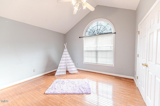 rec room with ceiling fan, light hardwood / wood-style flooring, and vaulted ceiling