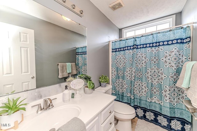 bathroom with a shower with curtain, vanity, a textured ceiling, and toilet