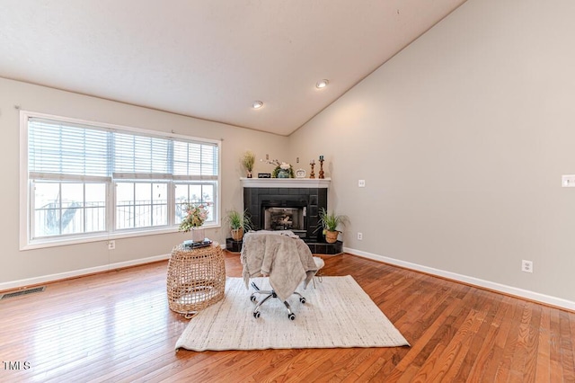 interior space with hardwood / wood-style floors, vaulted ceiling, and a tiled fireplace