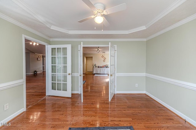 empty room featuring hardwood / wood-style floors, a raised ceiling, and ornamental molding