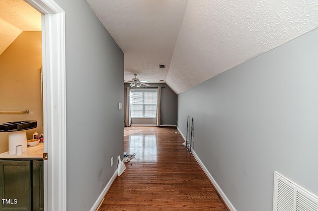 corridor featuring dark hardwood / wood-style flooring, a textured ceiling, and vaulted ceiling