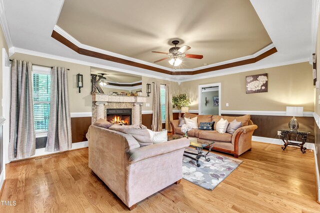 319 River Knoll Dr, Clayton, NC 27527 - living area with ornamental molding, a warm lit fireplace, a raised ceiling, wainscoting, and ceiling fan