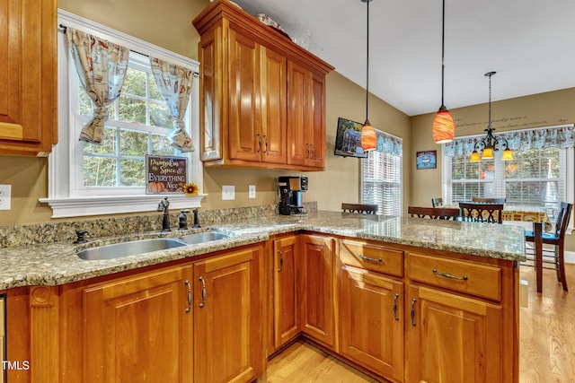 319 River Knoll Dr, Clayton, NC 27527 - kitchen featuring a sink, brown cabinetry, light stone counters, and a peninsula
