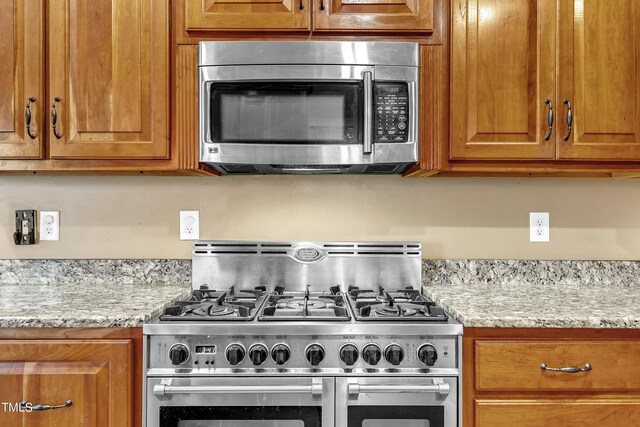319 River Knoll Dr, Clayton, NC 27527 - kitchen with brown cabinets, light stone counters, and stainless steel appliances