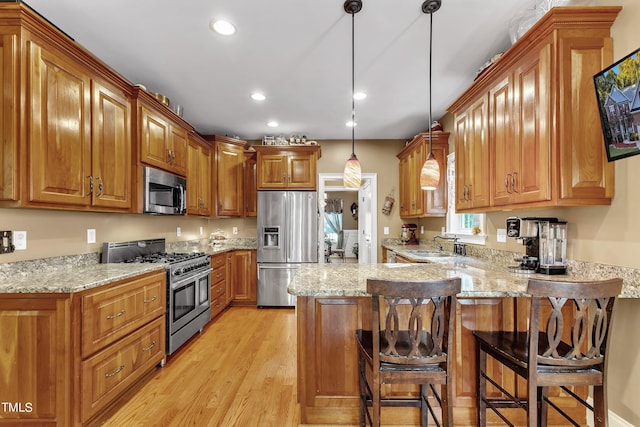 319 River Knoll Dr, Clayton, NC 27527 - kitchen with light stone countertops, a peninsula, light wood-type flooring, and appliances with stainless steel finishes