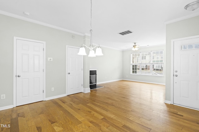 unfurnished living room featuring ceiling fan with notable chandelier, hardwood / wood-style floors, and crown molding