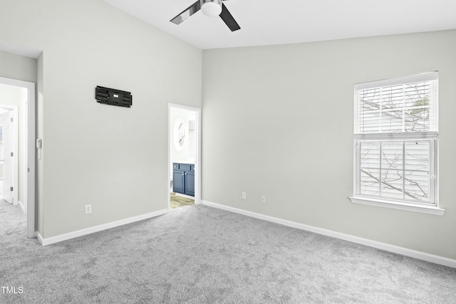 carpeted empty room featuring ceiling fan and vaulted ceiling