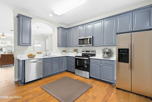 kitchen with stainless steel appliances, sink, gray cabinets, ceiling fan, and light hardwood / wood-style flooring