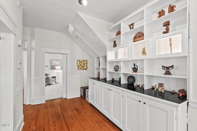 interior space featuring dark wood-type flooring, white cabinets, and vaulted ceiling