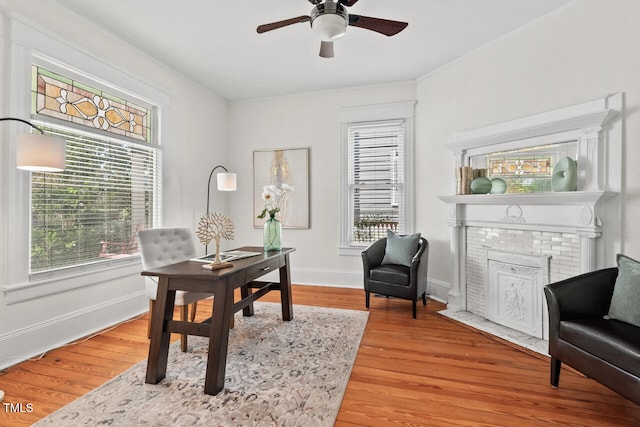 office with hardwood / wood-style floors, a fireplace, and ceiling fan