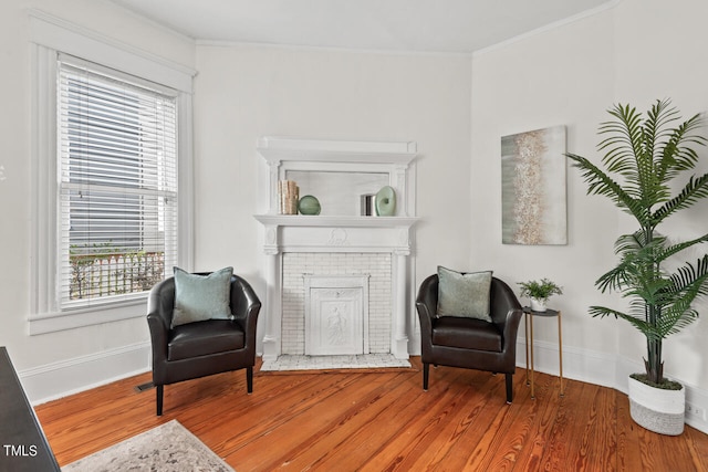 living area featuring a wealth of natural light, crown molding, a fireplace, and wood-type flooring