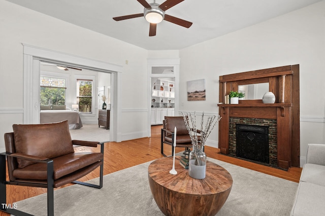 living room featuring a fireplace, light wood-type flooring, and ceiling fan