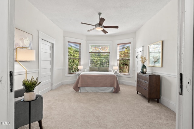 carpeted bedroom with ceiling fan, a textured ceiling, and multiple windows