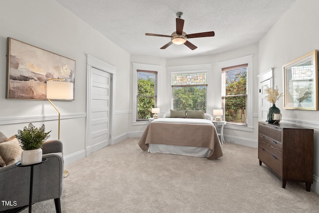 carpeted bedroom featuring ceiling fan, a textured ceiling, and multiple windows