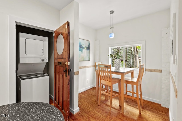 dining space with stacked washing maching and dryer and hardwood / wood-style floors