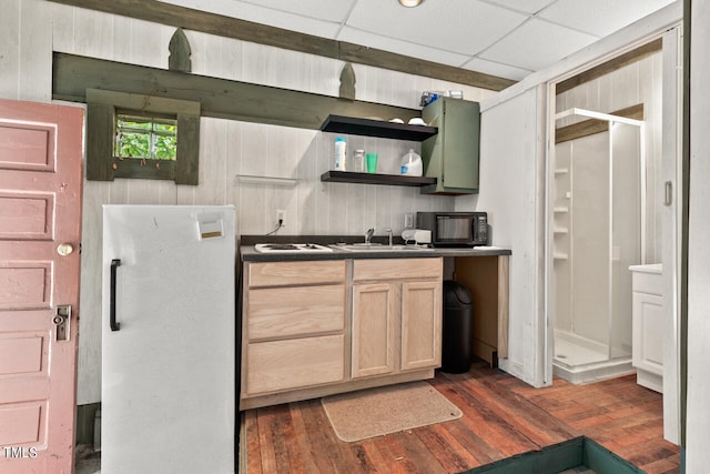 kitchen with light brown cabinets, dark wood-type flooring, sink, white fridge, and a paneled ceiling