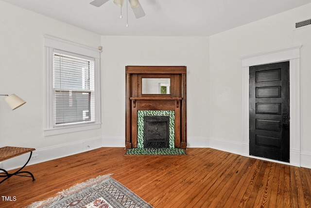 living room with hardwood / wood-style flooring, a tile fireplace, and ceiling fan