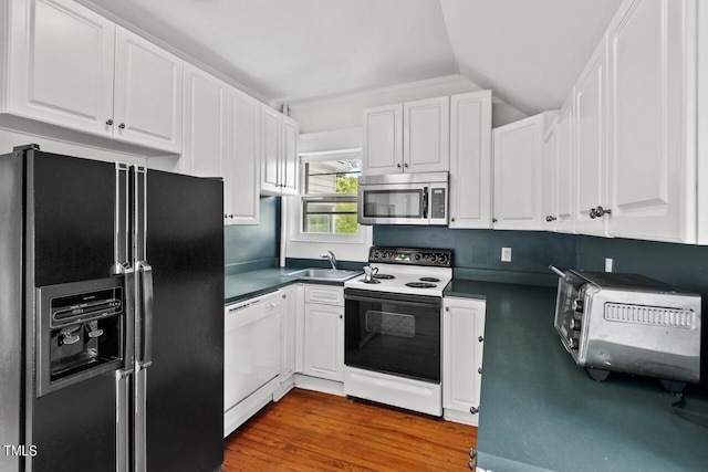 kitchen with hardwood / wood-style floors, vaulted ceiling, white cabinetry, and white appliances