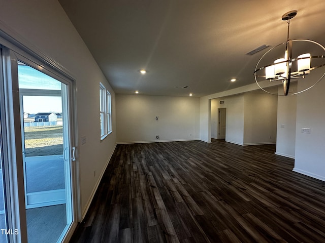 unfurnished living room with an inviting chandelier and dark hardwood / wood-style floors