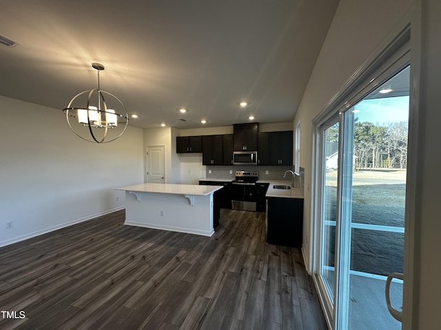 kitchen featuring dark wood-type flooring, sink, decorative light fixtures, a center island, and stainless steel appliances