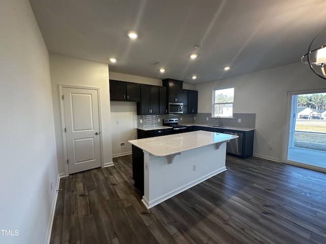 kitchen featuring a kitchen island, sink, backsplash, dark hardwood / wood-style flooring, and electric stove