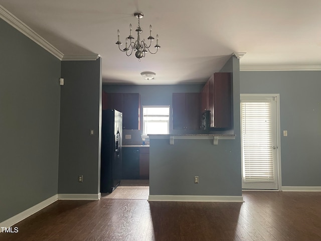 kitchen with hardwood / wood-style flooring, an inviting chandelier, ornamental molding, black appliances, and kitchen peninsula