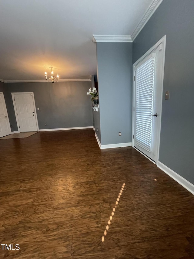 spare room with crown molding, dark hardwood / wood-style floors, and a chandelier