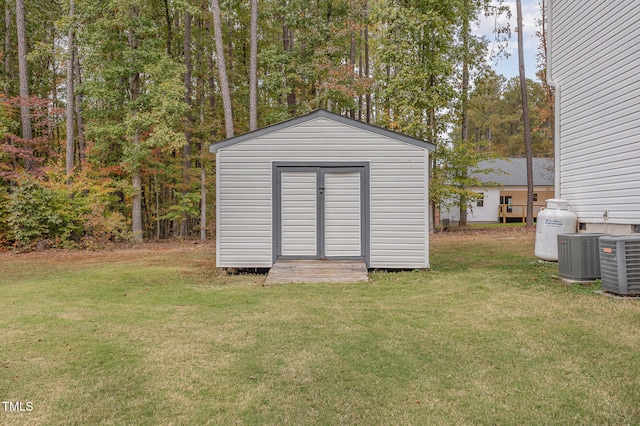 view of outdoor structure with central AC unit and a yard