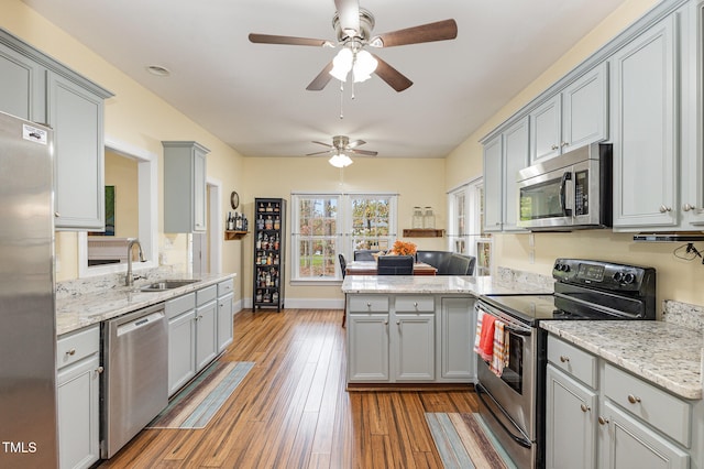 kitchen featuring kitchen peninsula, light hardwood / wood-style flooring, sink, gray cabinets, and appliances with stainless steel finishes