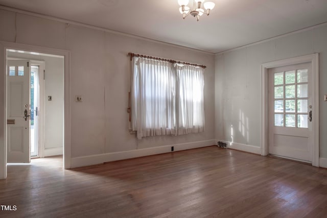 empty room featuring ornamental molding, hardwood / wood-style floors, and a notable chandelier