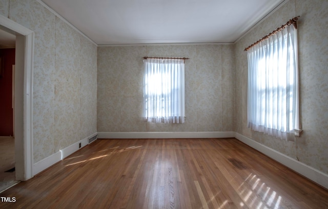 unfurnished room with wood-type flooring, plenty of natural light, and ornamental molding