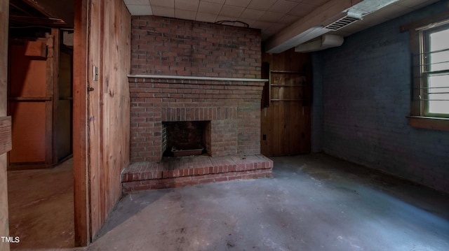 unfurnished living room featuring a brick fireplace, concrete floors, and a healthy amount of sunlight